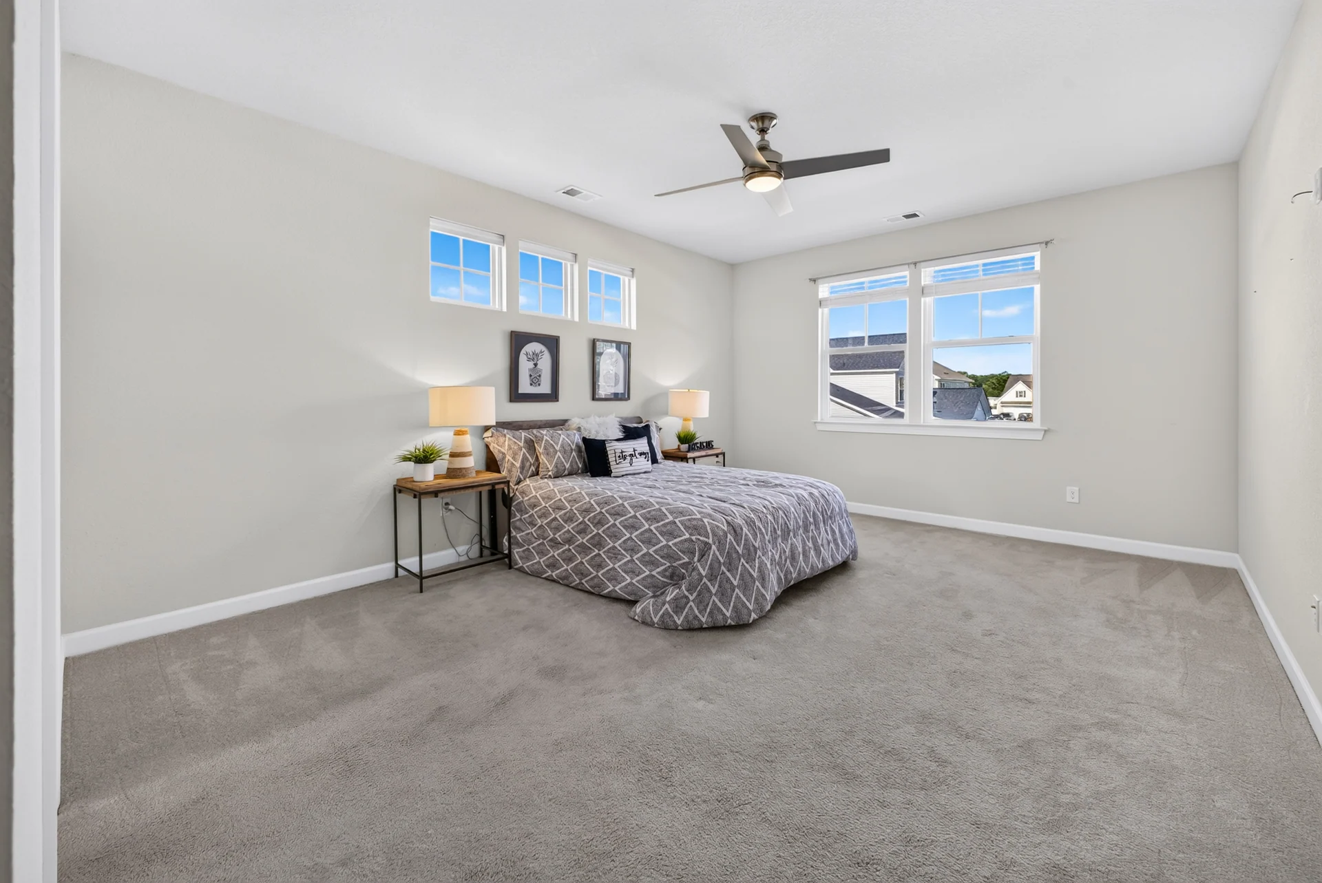 Carpeted bedroom with large windows and a ceiling fan