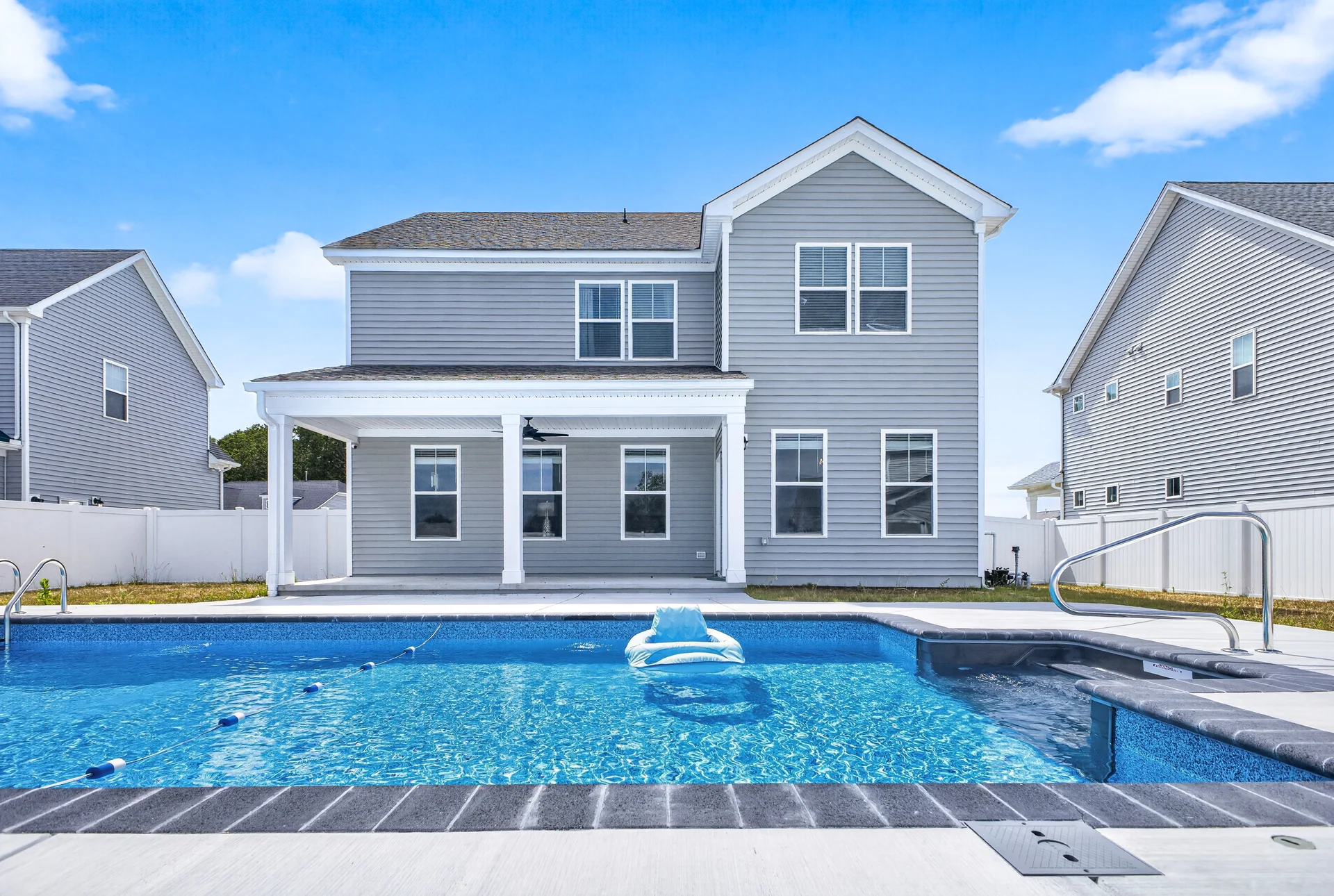 Rear view of a gray home beside a blue swimming pool